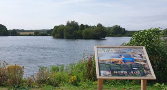 A lake with visitor interpretation board in the foreground.